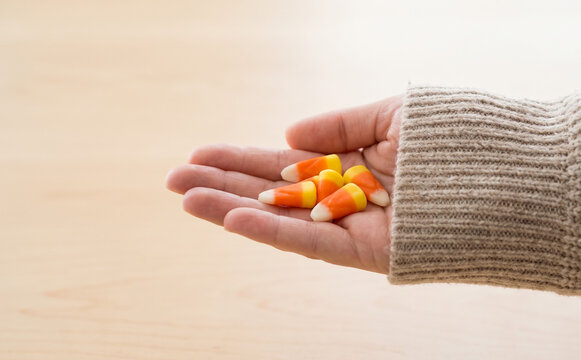 Woman holding handful of delicious sweet candy corn for Halloween celebration