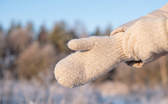 Woman wearing warm knitted wool mittens outdoors in winter representing cozy seasonal apparel