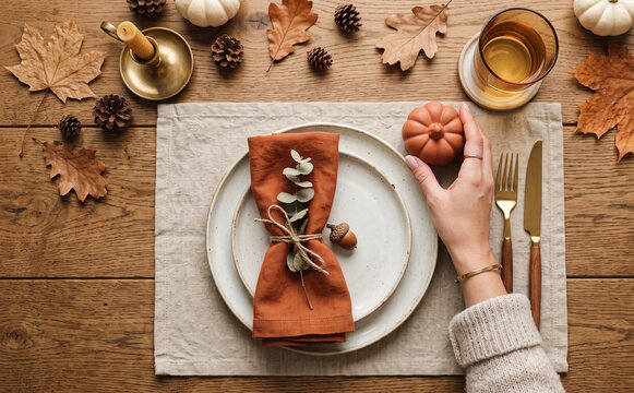 Autumn table setting with a place mat plates napkin and mini pumpkin on a wooden background