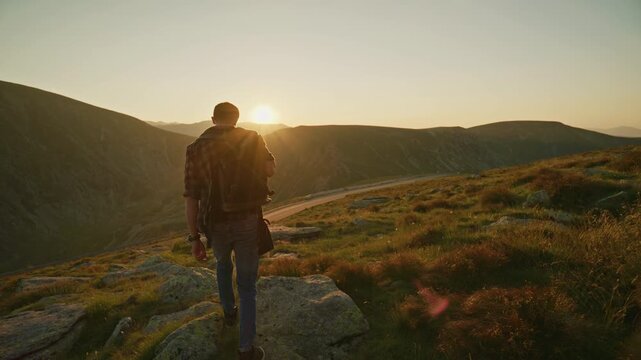 Hiker walks along mountain trail during sunset in a natural setting