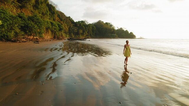 Woman enjoying golden hour while walking on secluded sandy each in Costa Rica