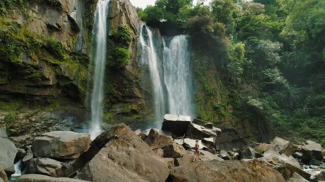 Adventurer approaching massive waterfalls in lush tropical jungle of Costa Rica