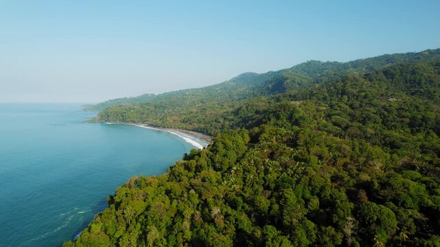 Green hills and quiet curving bay on Costa Rica coast in soft morning
