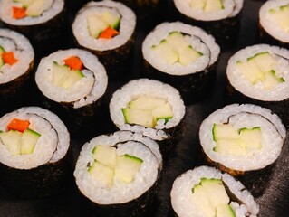 Top view close-up of vegetarian maki sushi rolls with cucumber and carrot on a black tray © Robert