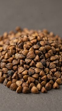 Dry organic buckwheat groats piled on grey background with close up macro detail