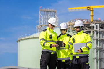 Industrial engineers team with digital tablet and laptop discussing plant project, Workers reviewing data at oil and gas facility, Team of industrial experts collaborating at construction site © iPoguz