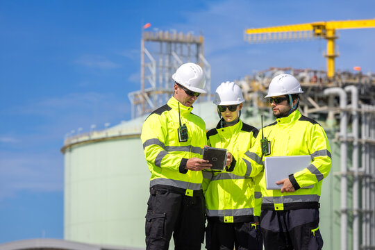 Industrial engineers team with digital tablet and laptop discussing plant project, Workers reviewing data at oil and gas facility, Team of industrial experts collaborating at construction site