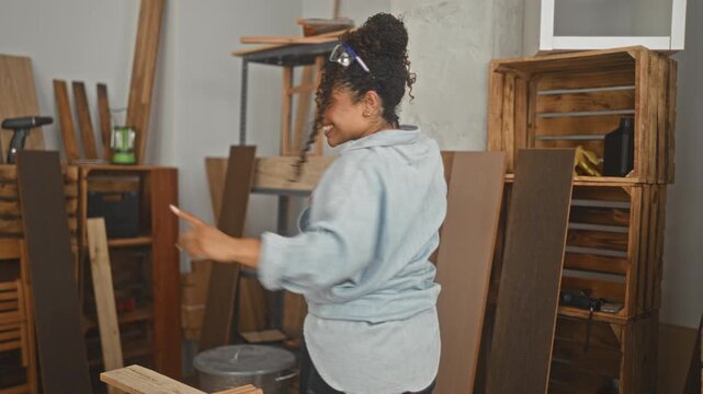 Woman dancing with outstretched hands over a wood plank and measuring tape while smiling in a studio; craft pride joy.