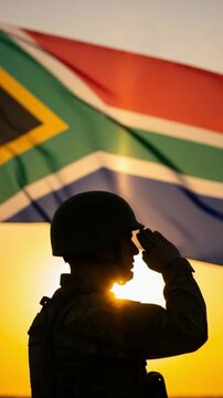 Silhouette of a male soldier saluting in front of the South African flag at sunset representing patriotism and military service