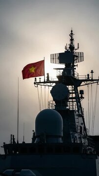 Vietnamese Navy warship silhouette with national flag flying at sunset representing maritime defense, patriotism, and military power in Asia