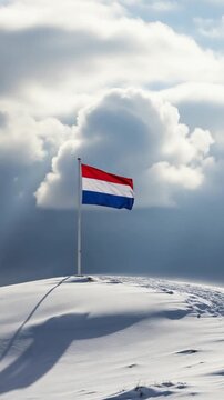 Dutch flag waving proudly on a snowy hill under dramatic cloudy sky representing winter patriotism and national pride
