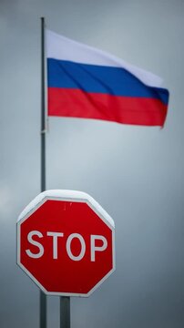 Russian flag waving behind a red stop sign symbolizing geopolitical conflict and protest against Russia