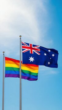Australian and rainbow pride flags waving together against a bright blue sky symbolizing LGBTQ community support and national identity in Australia