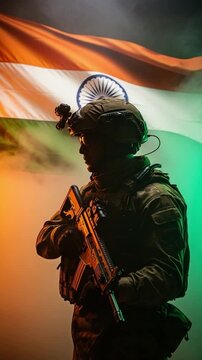Indian soldier in tactical gear holding rifle in front of national flag representing patriotism and defense
