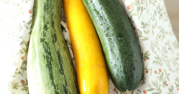 Woman with many fresh raw zucchinis at table, closeup