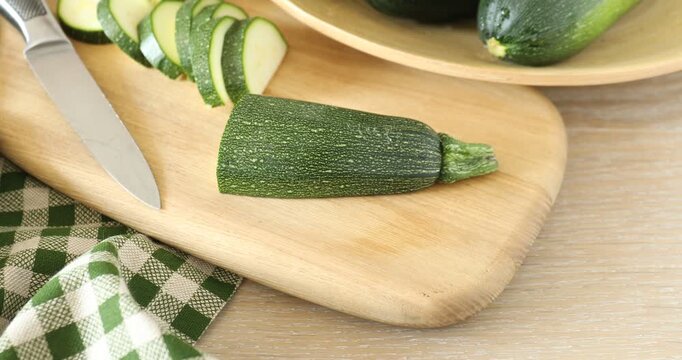 Fresh raw zucchinis and knife on wooden table, closeup. Camera moving forward