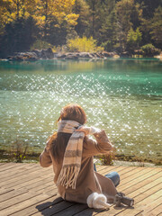 Woman sitting on wooden dock admiring turquoise lake, Blue Moon Valley, Lijiang © nhat.photograph