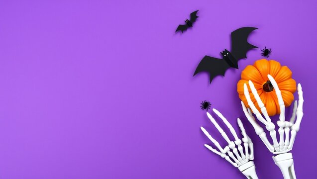 Skeleton hands holding a pumpkin with bats flying on a purple background for halloween