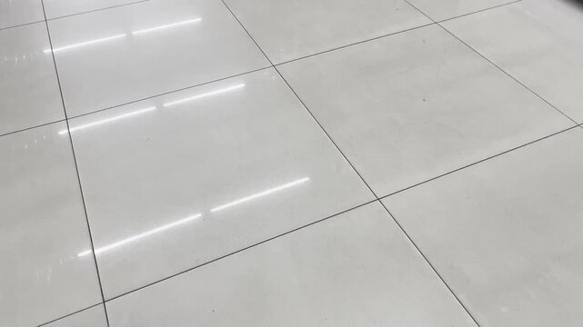 Polished ceramic flooring tile background with linear lighting overlay