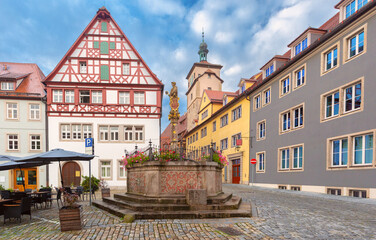 Fototapeta premium Traditional half-timbered buildings and an ornate stone fountain on a cobblestone square in Rothenburg ob der Tauber, Germany.
