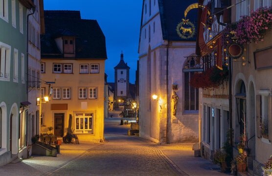 Half-timbered houses and cobblestone streets illuminated by warm streetlights during blue hour in Rothenburg ob der Tauber, Germany.