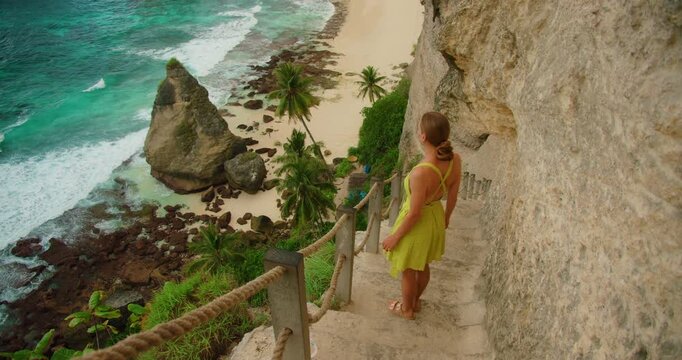 Female traveler waking sown steep stone steps looking at Diamond Beach during summer trip