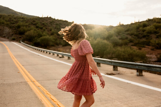 Young Woman Twirling in Desert Road
