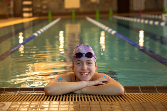Teen girl smiling at edge of indoor swimming pool