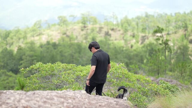 Man in Black Clothes Descending Mountain Trail with Pet Dog