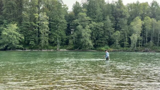 Mature retired man fly fishing the Skagit river in Washington state Cascades during summer season while performing the single spey cast 