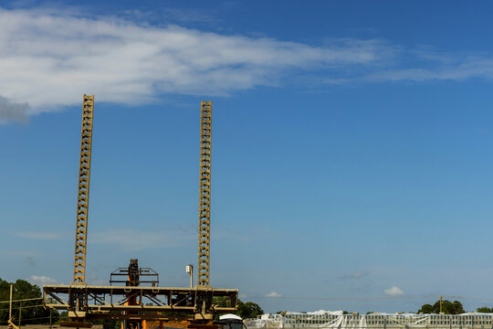 Workers are setting up structures at construction site under blue sky with some clouds.
