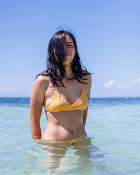 Woman in a yellow bikini standing in clear tropical water in the Philippines