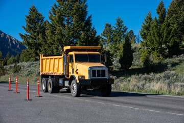 Summer construction season, bright yellow dump truck on road, summer vacation at Yellowstone National Park  © knelson20