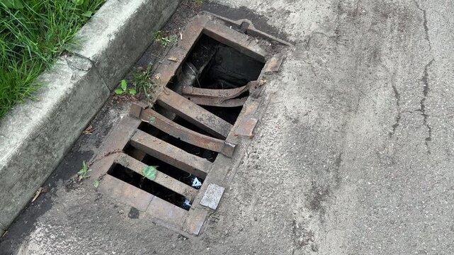 Broken Storm Drain Grate on Roadside Curb | Damaged Rusty Sewer Grille with Missing Bars | Urban Infrastructure Disrepair Close-Up Shot