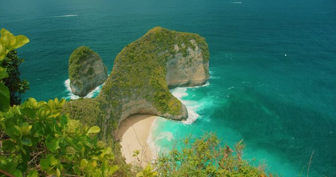 Scenic view of Kelingking Beach cliffs through tropical foliage in Nusa Penida Bali