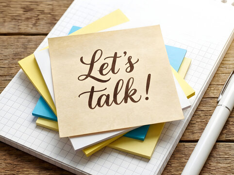 Sticky note with let's talk text on a wooden desk