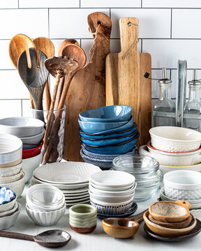Stacks of various bowls and other dishes against a white subway tile background.