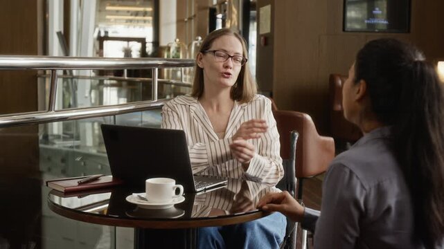 Portrait of Caucasian woman with disability in wheelchair shaking hands with Hispanic female colleague during business meeting. Perfect for corporate diversity and inclusion campaigns