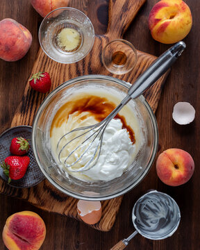 A bowl of ingredients being mixed for making a homemade strawberry peach cake. 