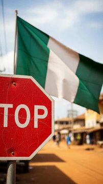 Nigerian Flag and Stop Sign on Dusty Street in West Africa Representing Traffic Rules and National Identity