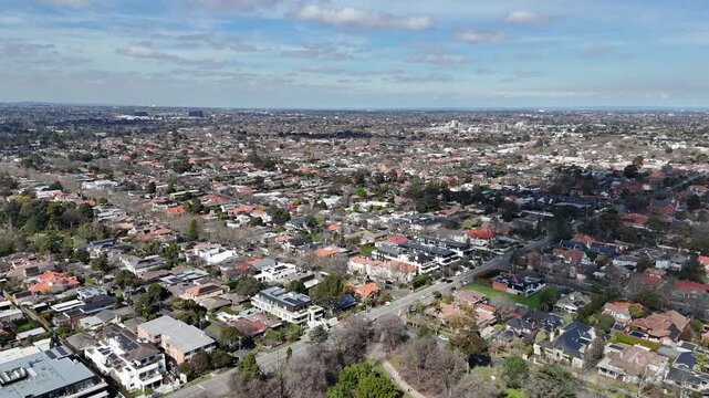 Aerial view over leafy neighborhoods with houses and apartment complexes stretching toward the distant horizon in Malvern East, Melbourne, Australia. Concepts of density, residential living