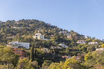 Naklejka premium Provence, France , December 31, 2025: Upscale Mediterranean villas cling to steep volcanic rocks of the Esterel Massif between Cannes and Nice.