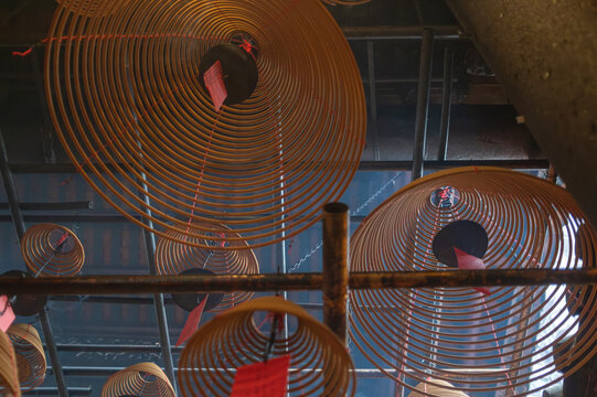 Hanging incense coils release thick smoke above devotees praying at the historic Man Mo Temple.