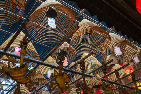 Hanging incense coils release thick smoke above devotees praying at the historic Man Mo Temple.