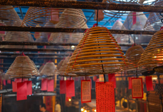 Hanging incense coils release thick smoke above devotees praying at the historic Man Mo Temple.