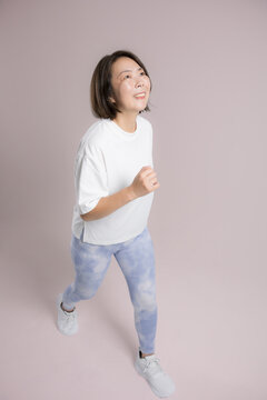[ピンク背景]笑顔でランニングやウォーキングを楽しむ女性、健康維持のために運動するアクティブな40代