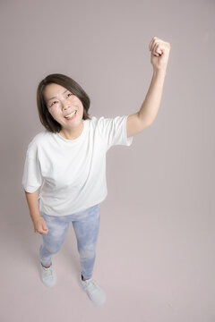 [Pink Background] A woman exercising with a smile and her arms raised high in a victory pose; a fitness image depicting a healthy, positive, and successful dieter in her 40s