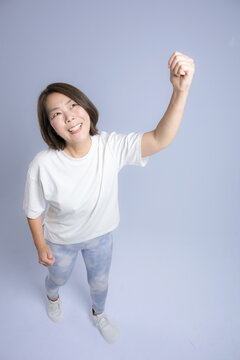[Blue Background] A woman exercising with a smile and her arms raised high in a victory pose; a fitness image representing successful weight loss and a healthy, positive outlook for people in their 40