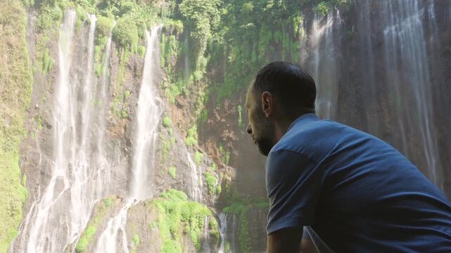 Man watching a beautiful cascading waterfall
