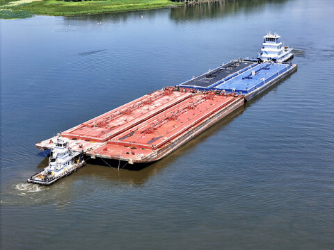 Set of liquid cargo barges being guided by a small service tug
